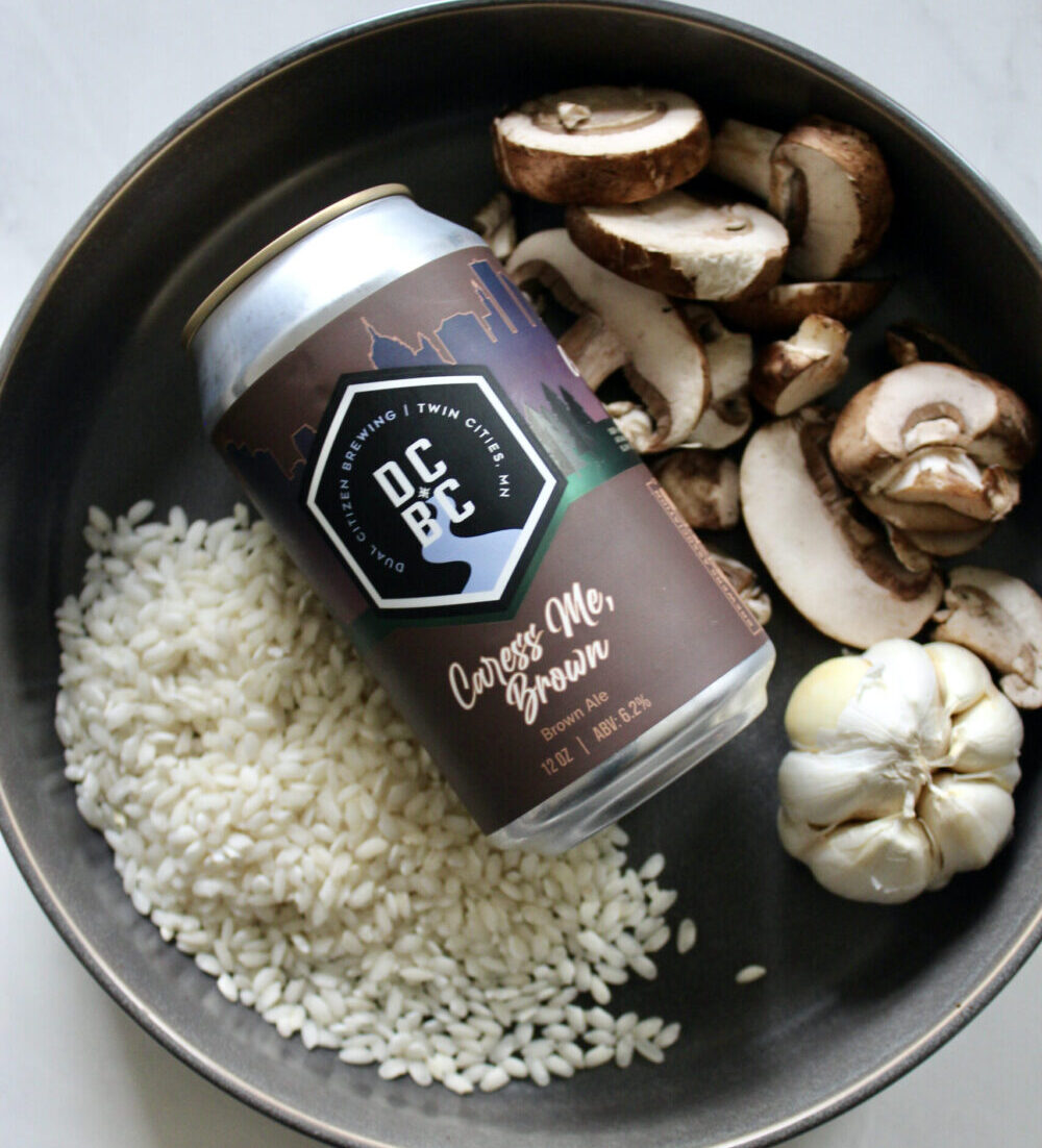 bowl with raw ingredients including rice, mushrooms and garlic, with a can of beer in the middle